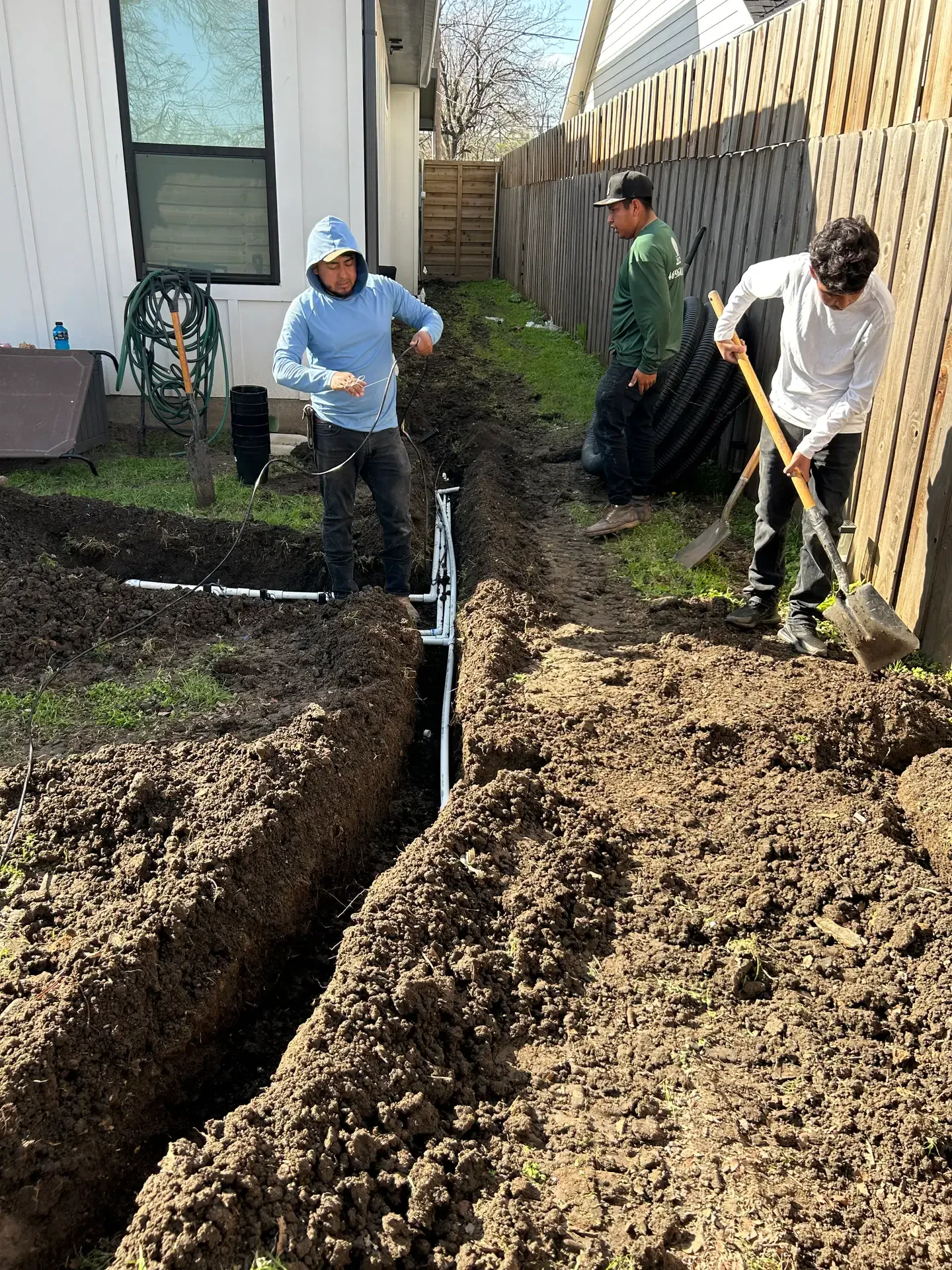 crew installing underground lines by fence